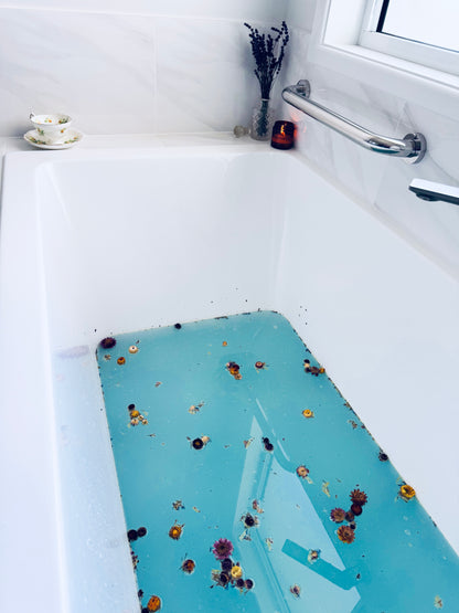 Blue tinged water with dried flowers floating in it.