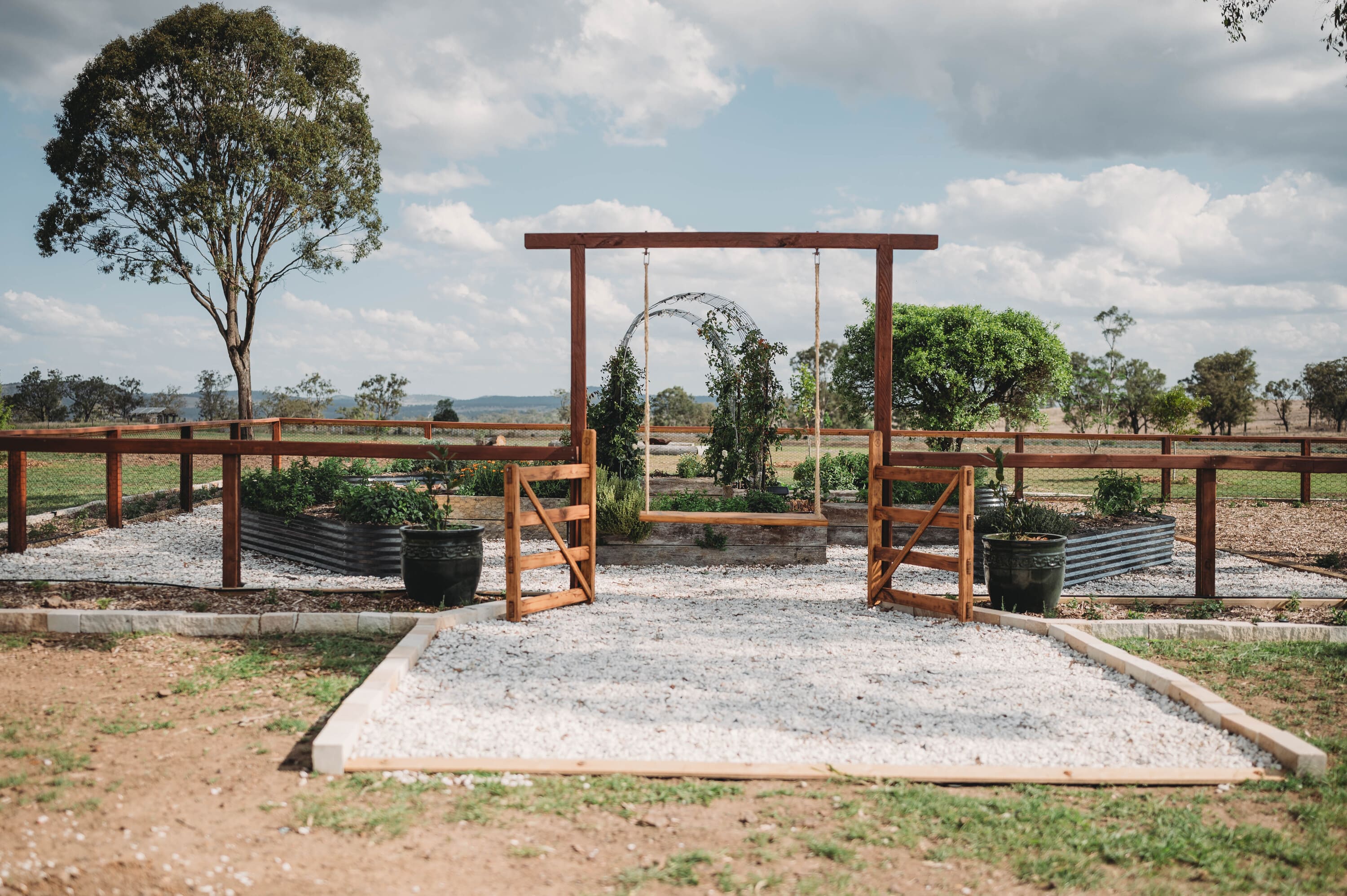 Outdoor setting with a wooden swing set and garden area.