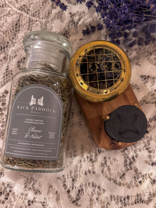 Glass jar of loose smoke dried lavender and rosemary flowers, with a burner on a timber stand with charcoal blocks.
