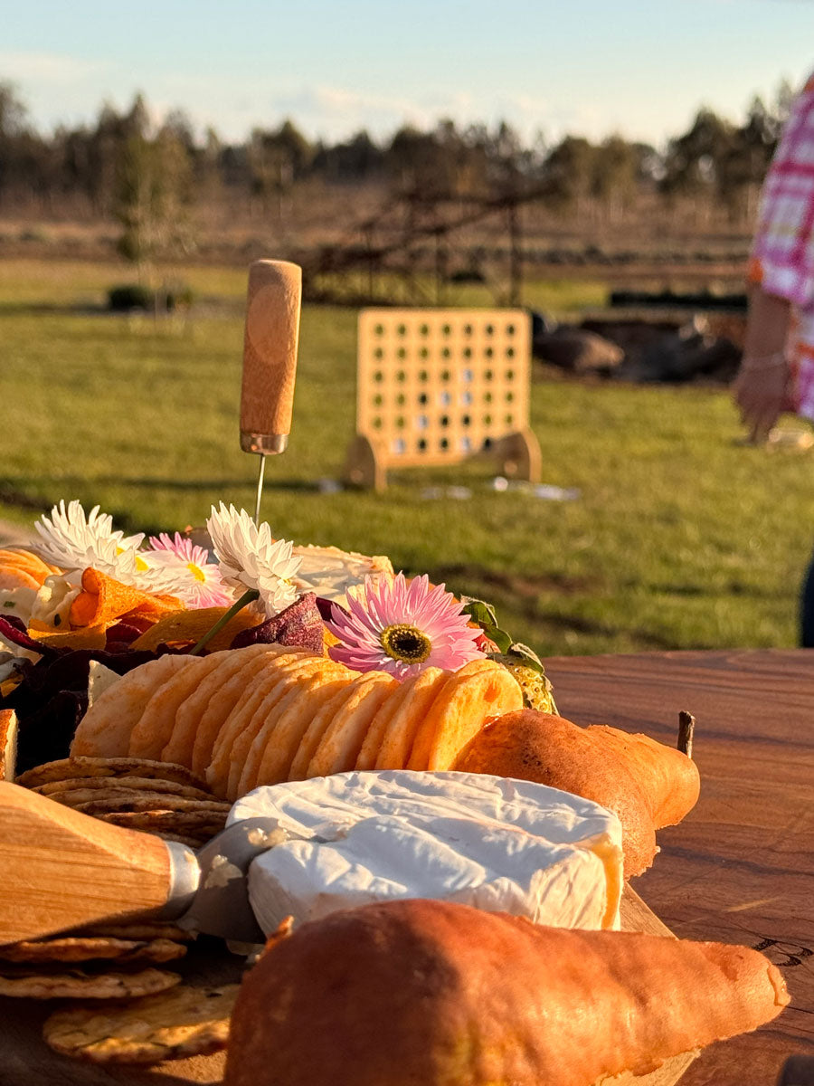 Cheese, crackers and flowers on a timber board overlooking the lavender farm set up with games