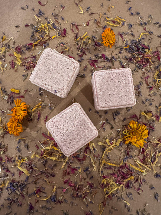 3 cube shower steamers infused with lavender essential oil, on a bed of dried flowers.