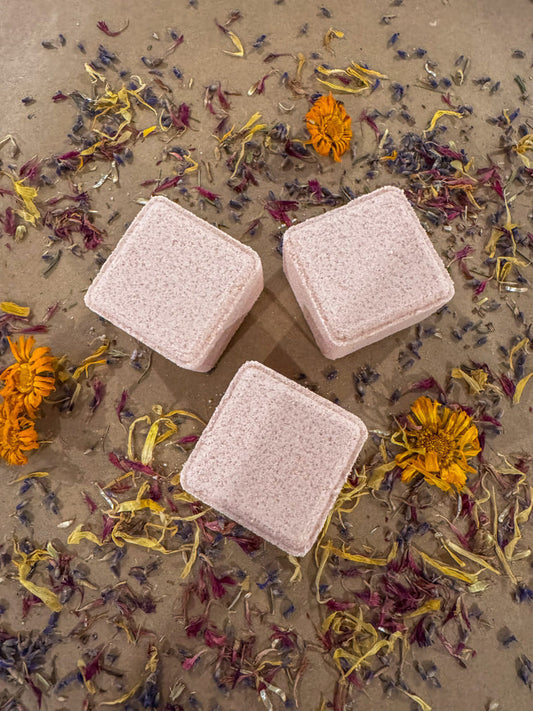 3 cube shower steamers infused with lavender, white cypress and buddha wood essential oils, in a bed of dried flowers.
