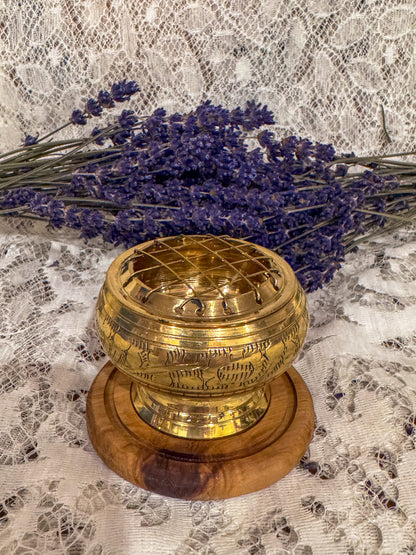 Gold incense burner object on a wooden base with lavender flowers on a lace background
