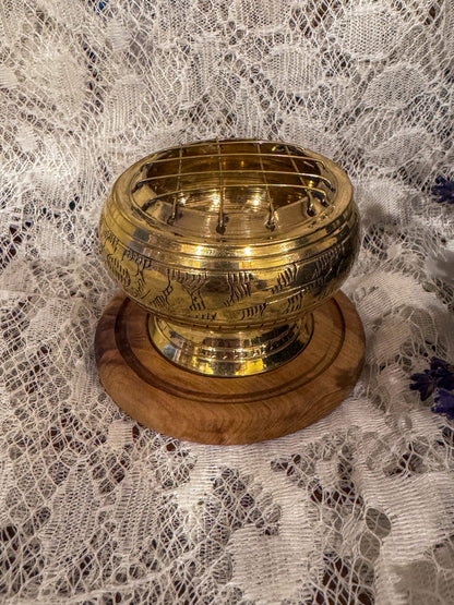 Metal incense burner for smoke cleansing on a round timber base, sitting on a lace backdrop with lavender buds.