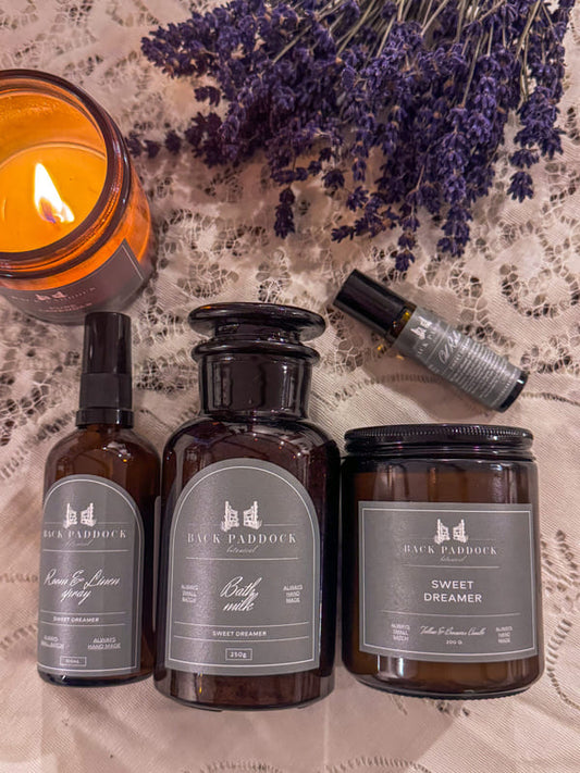 Collection of Black Paddock products including bottles and a candle on a textured surface with lavender.